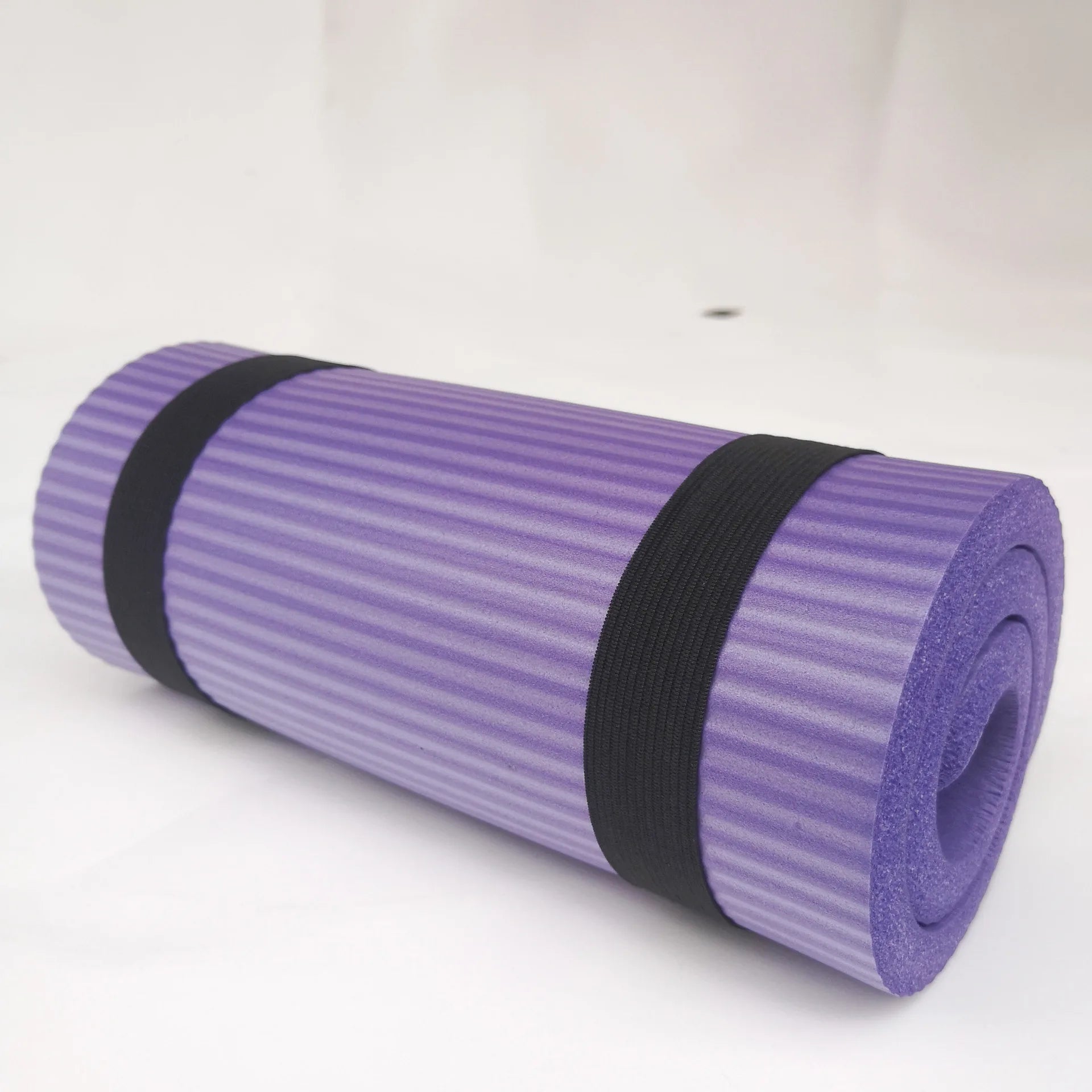 Purple yoga mat rolled up with straps