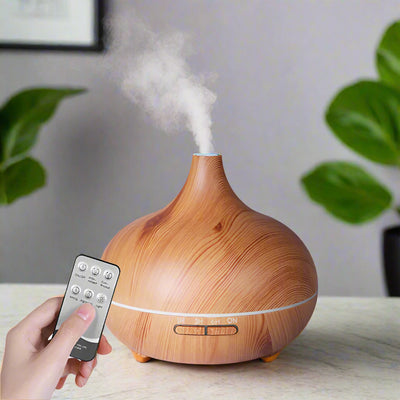 TranquilMist Pro aromatherapy diffuser with wood grain design emitting mist, remote control in hand.